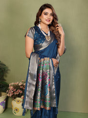 Woman wearing a blue and silver saree with a green background