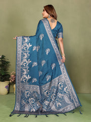 Woman wearing a blue saree with white patterns against a green background