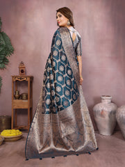Woman wearing a traditional blue and silver saree in a decorative setting with vases and plants.
