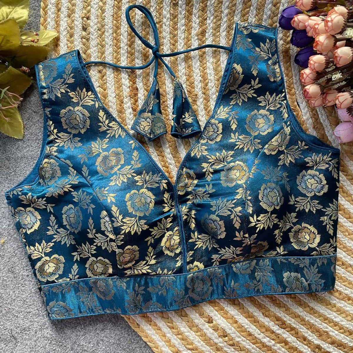 Blue floral-patterned top on a textured surface with flowers in the background