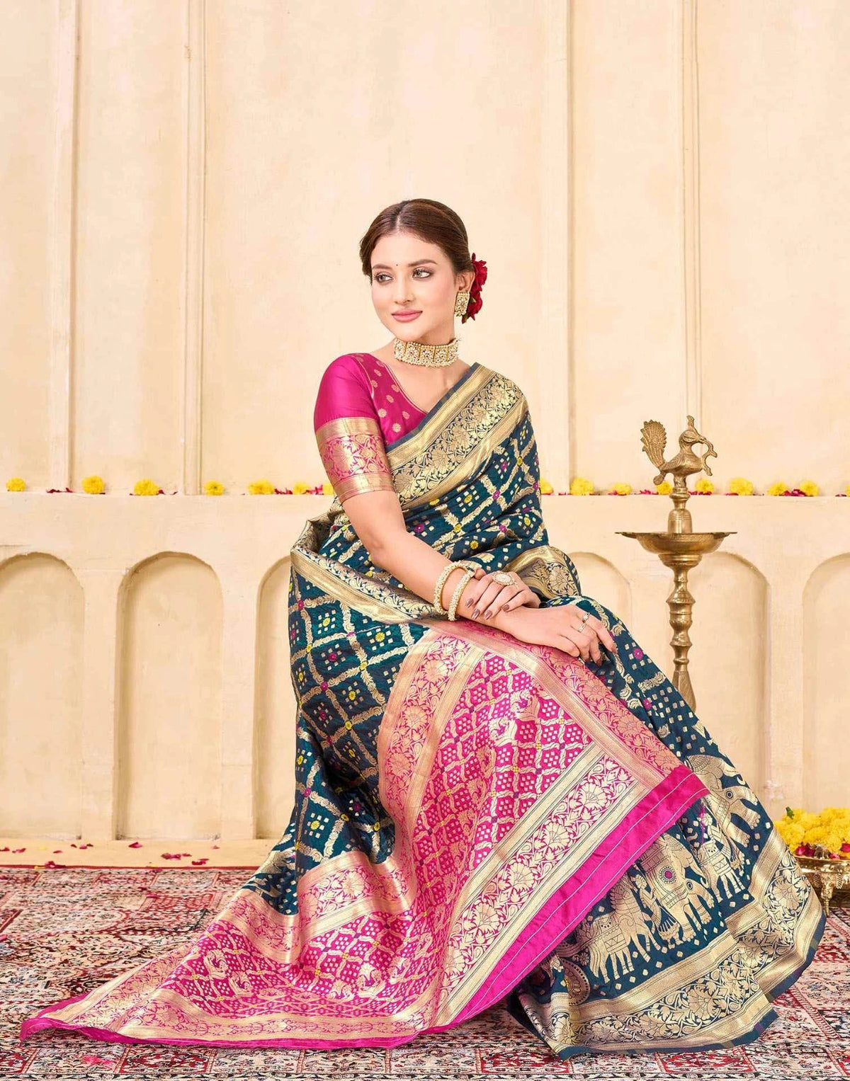 Woman in a traditional saree sitting on a decorative platform with a neutral background