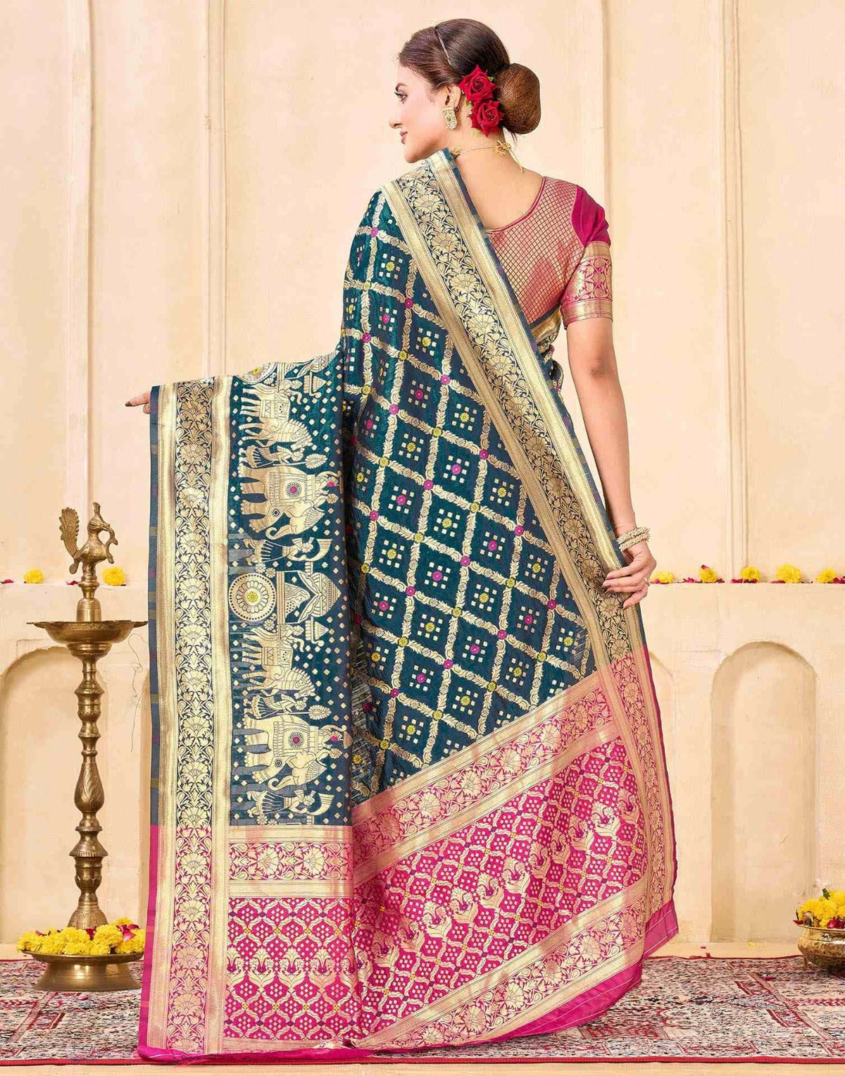 Woman wearing a traditional saree with intricate patterns in a decorated indoor setting