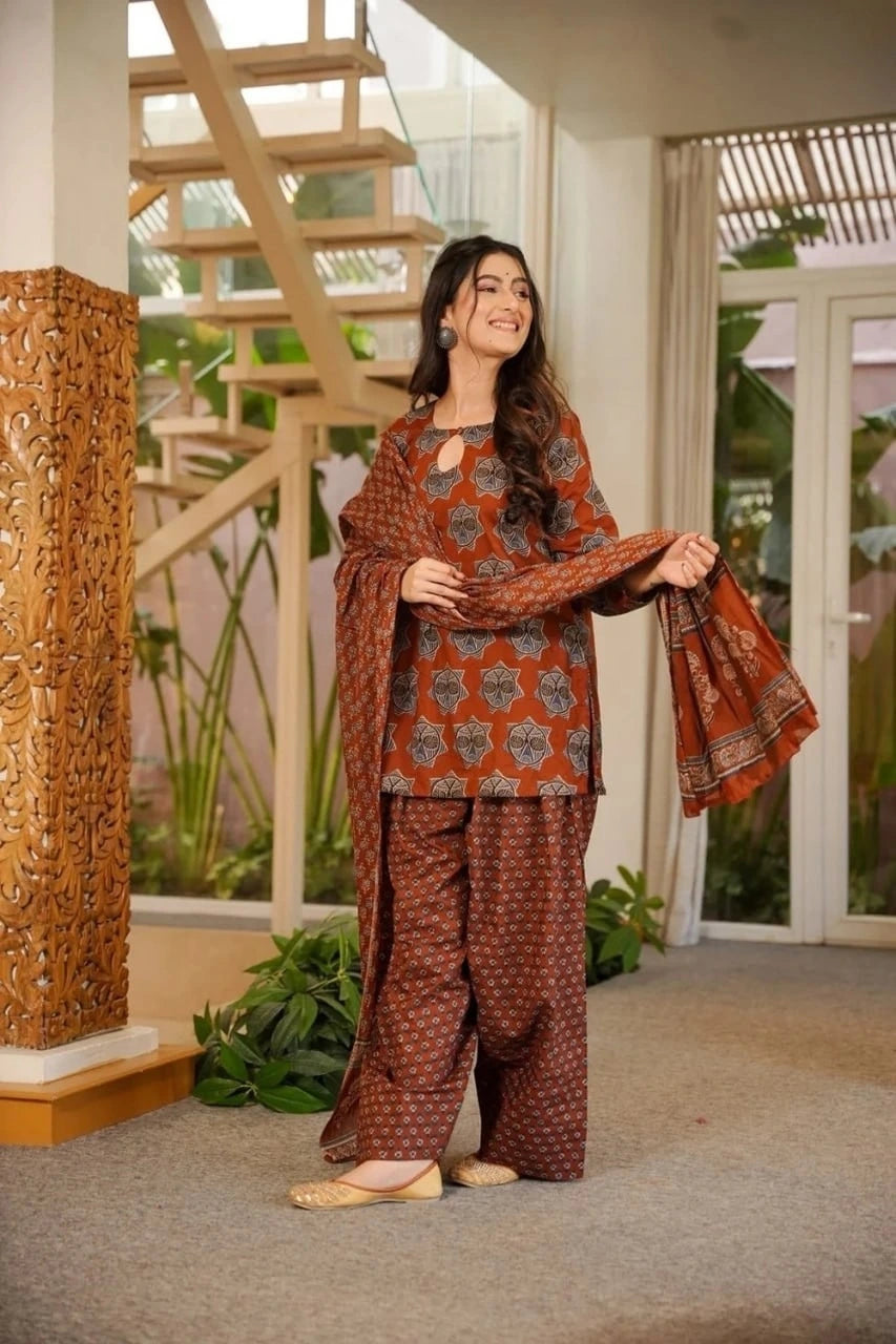Woman wearing a patterned outfit standing indoors with decorative elements in the background