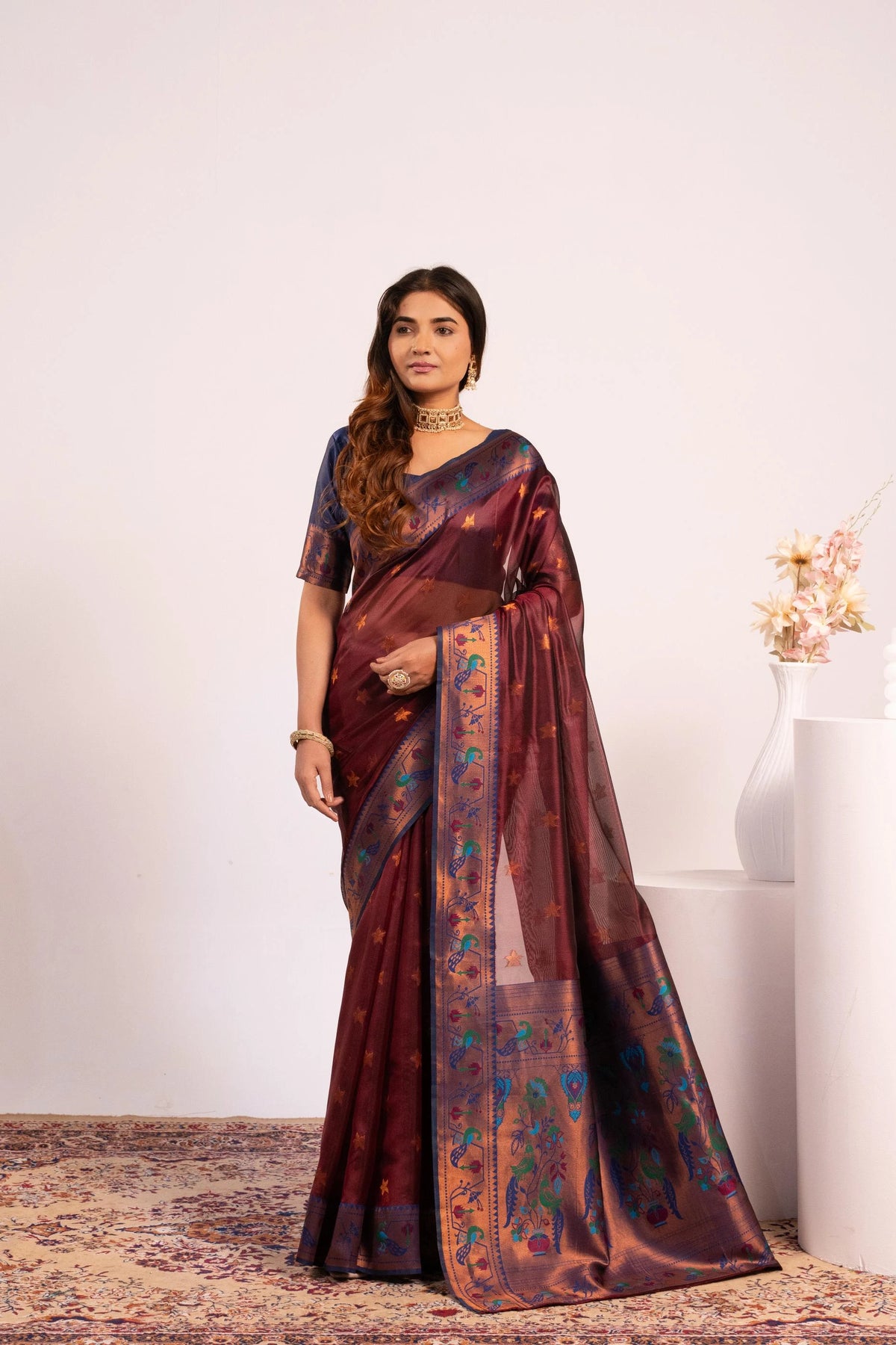 Woman wearing a maroon saree with a floral pattern on a white background