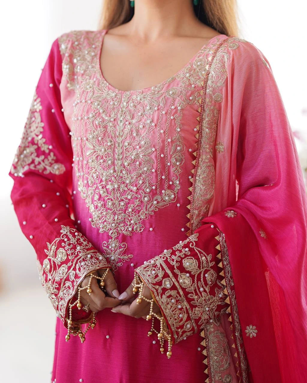 Pink embroidered traditional outfit with gold details on a white background