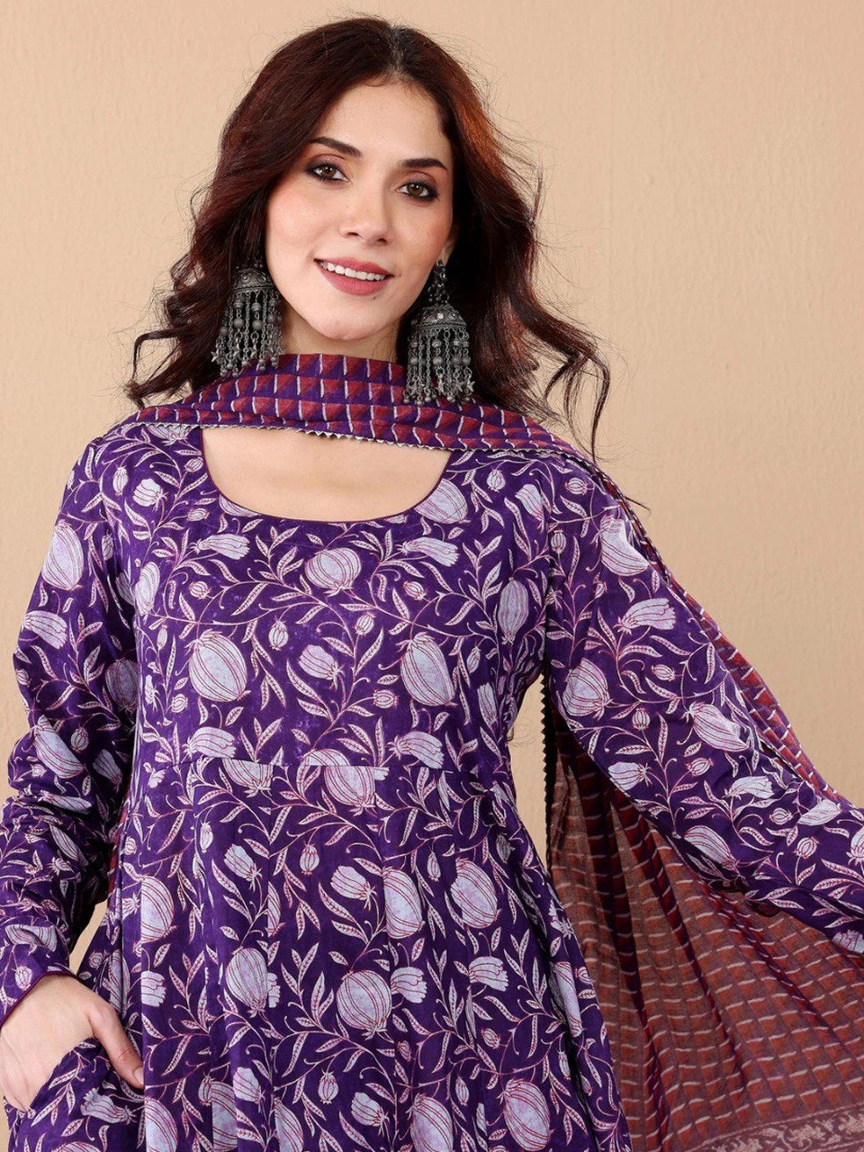 Woman wearing a purple patterned outfit with a beige background