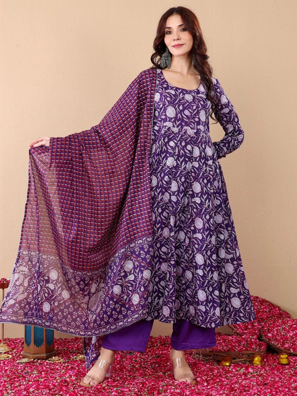 Woman wearing a purple patterned outfit with a matching dupatta on a beige background