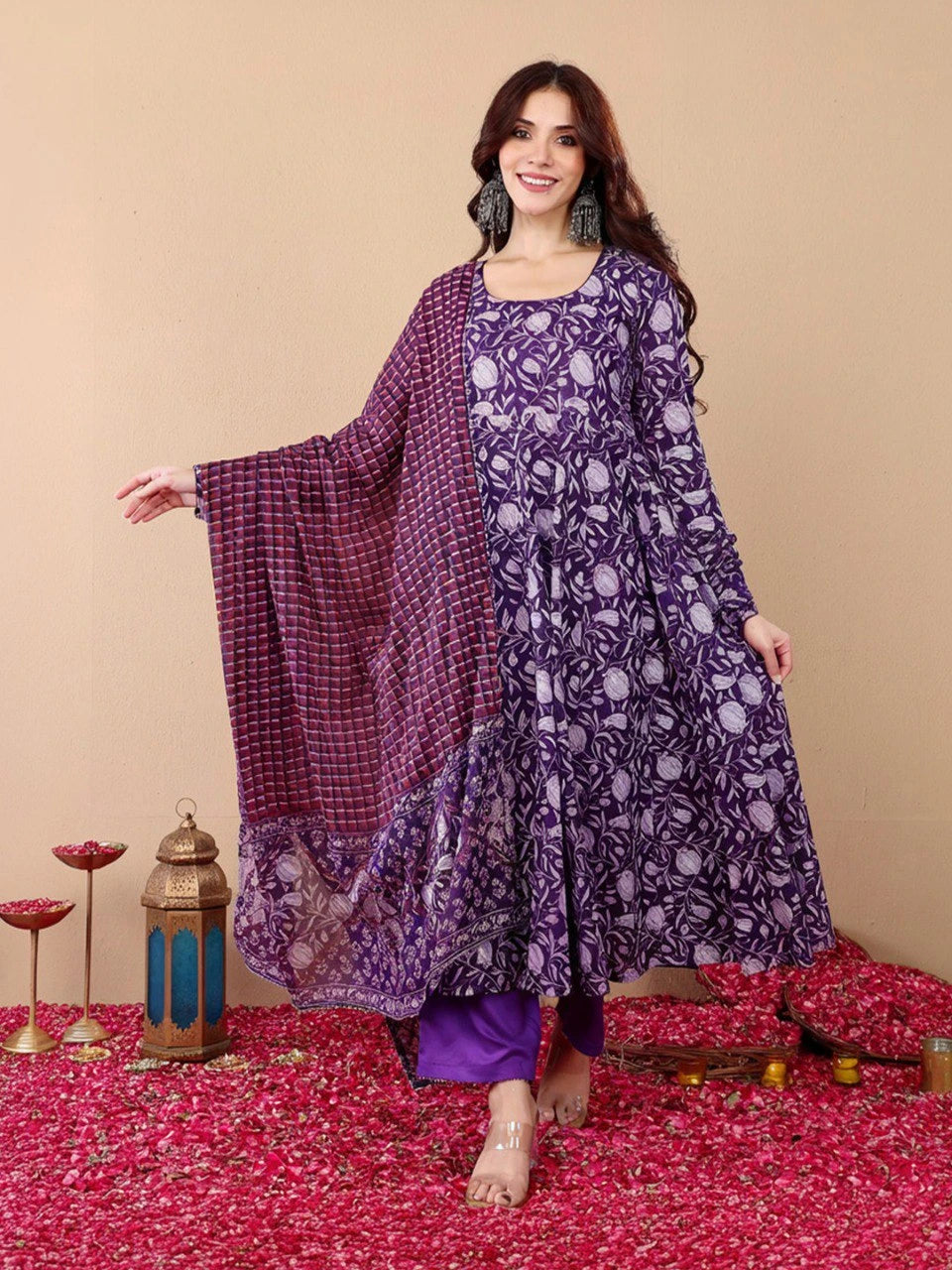 Woman wearing a purple floral outfit with a matching dupatta on a decorated floor.