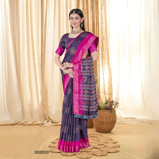 Woman in a deep shade purple sequence jacquard work saree with pink border standing indoors against a backdrop of beige curtains and woven decor elements