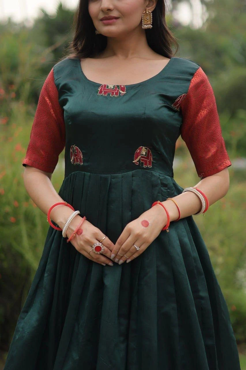 Woman wearing a green and red traditional outfit with intricate designs, standing outdoors.