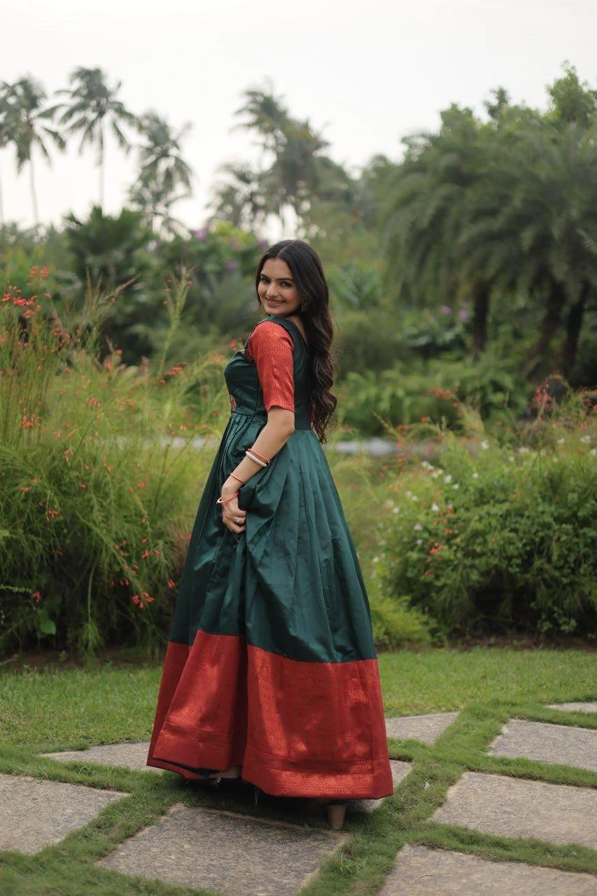 Woman in a green and red traditional outfit standing in a garden.