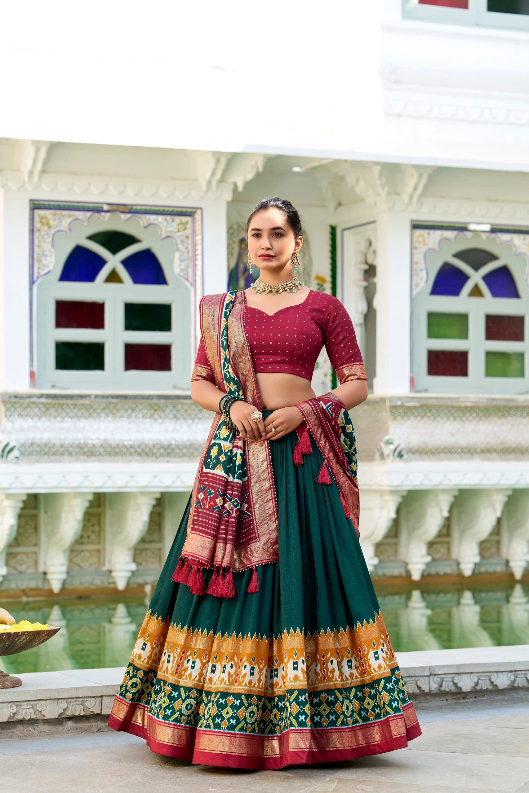 Woman in traditional outfit standing in front of a decorative building with stained glass windows.
