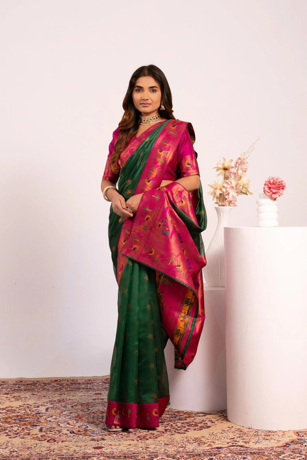 Woman wearing a green and pink saree with a white background