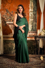 Woman in a green saree standing in an ornate room with decorative wall art.