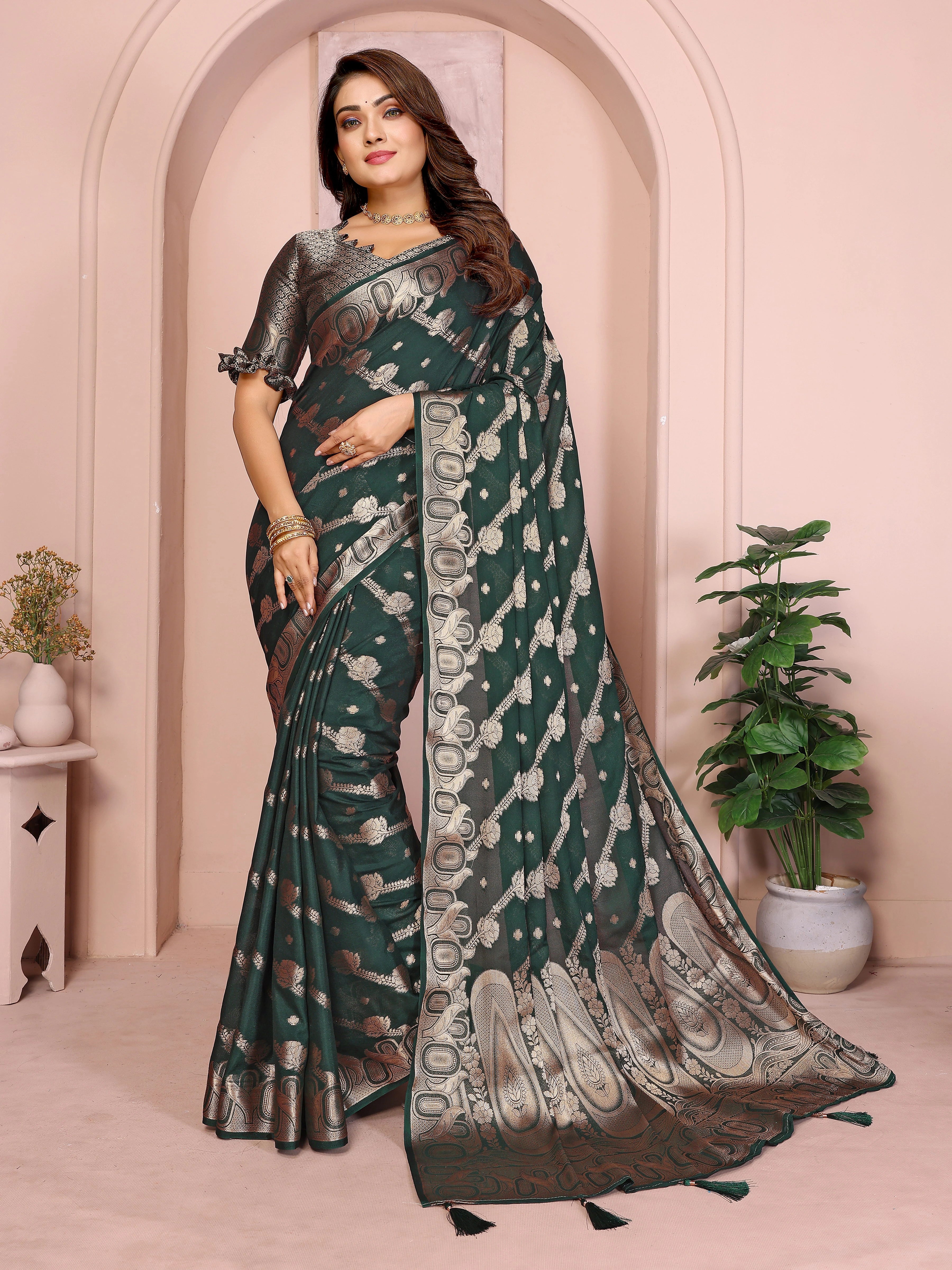 Woman wearing a green saree with a white border in an elegant indoor setting.