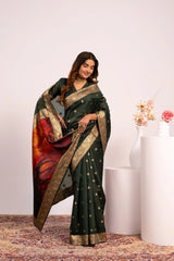 Woman wearing a dark green saree with a colorful pattern, standing against a white background.