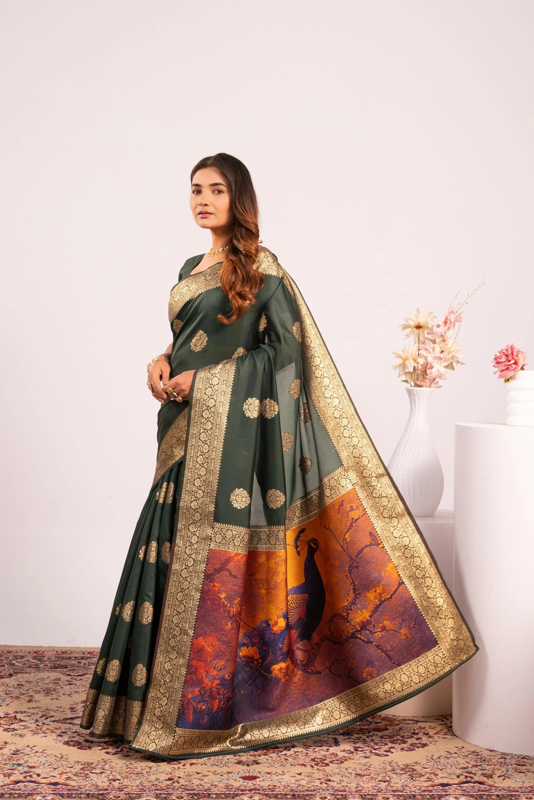 Woman wearing a traditional green saree with gold and orange patterns on a white background