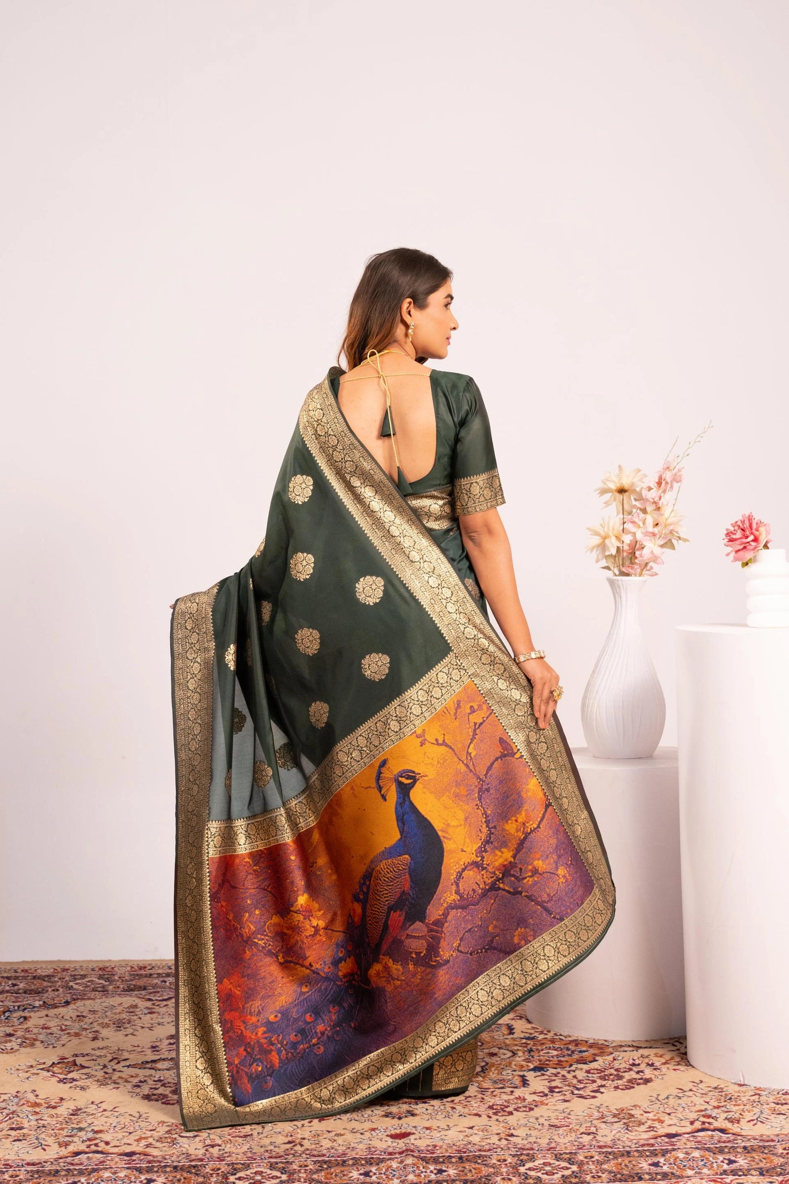 Woman wearing a saree with a deer design, standing in a minimalistic room.