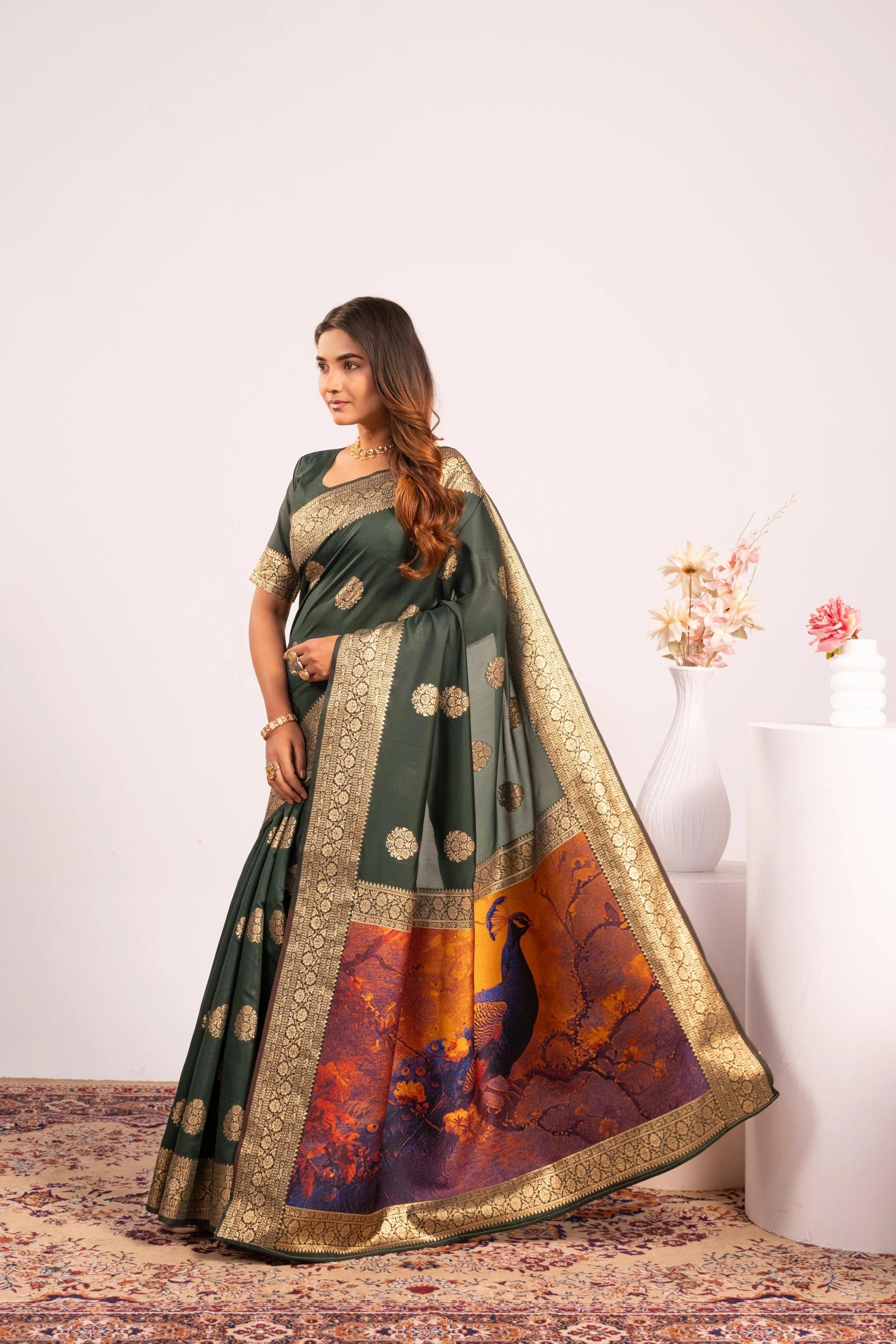 Woman wearing a traditional saree with a colorful design on a plain background