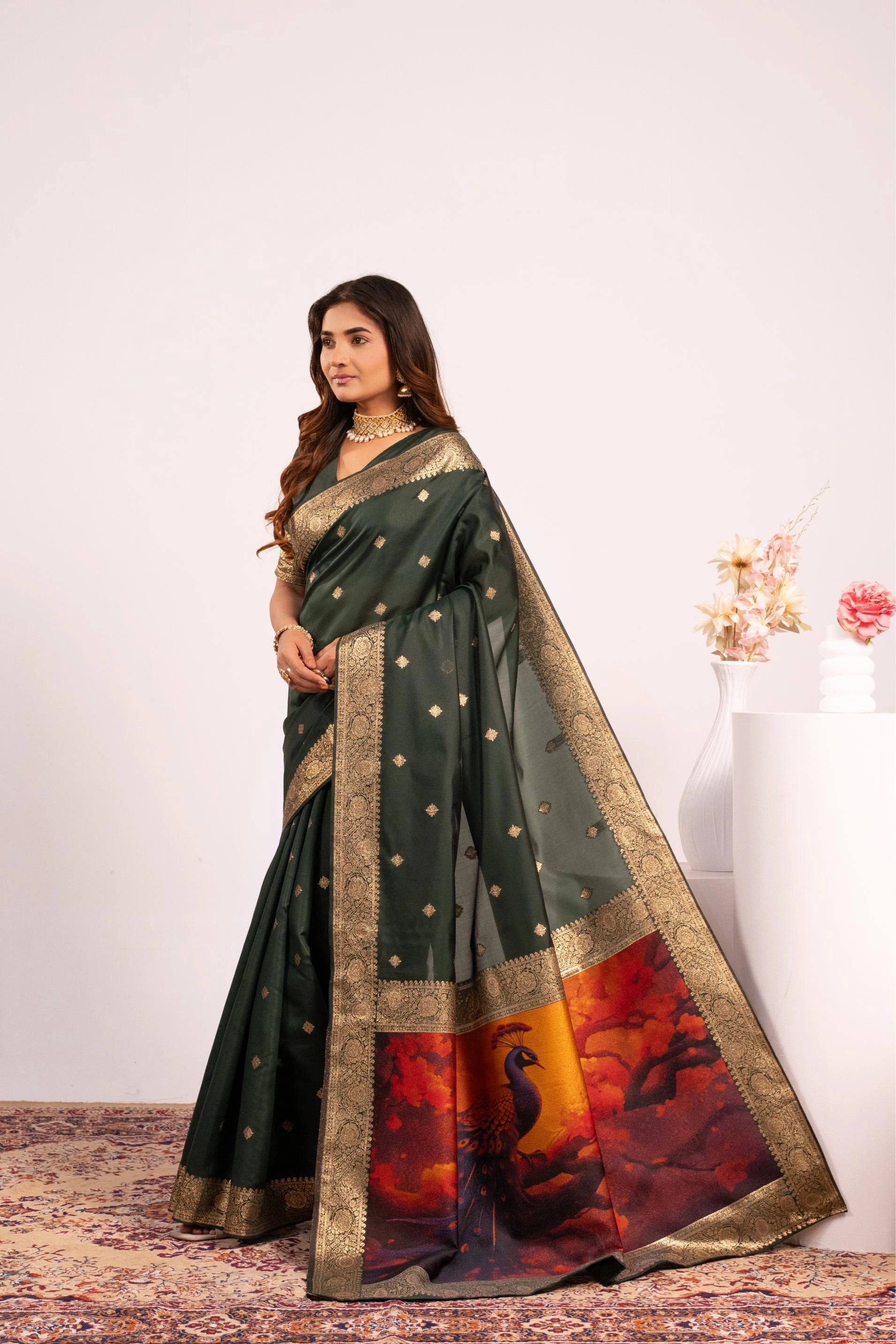 Woman wearing a dark green saree with a colorful border on a white background