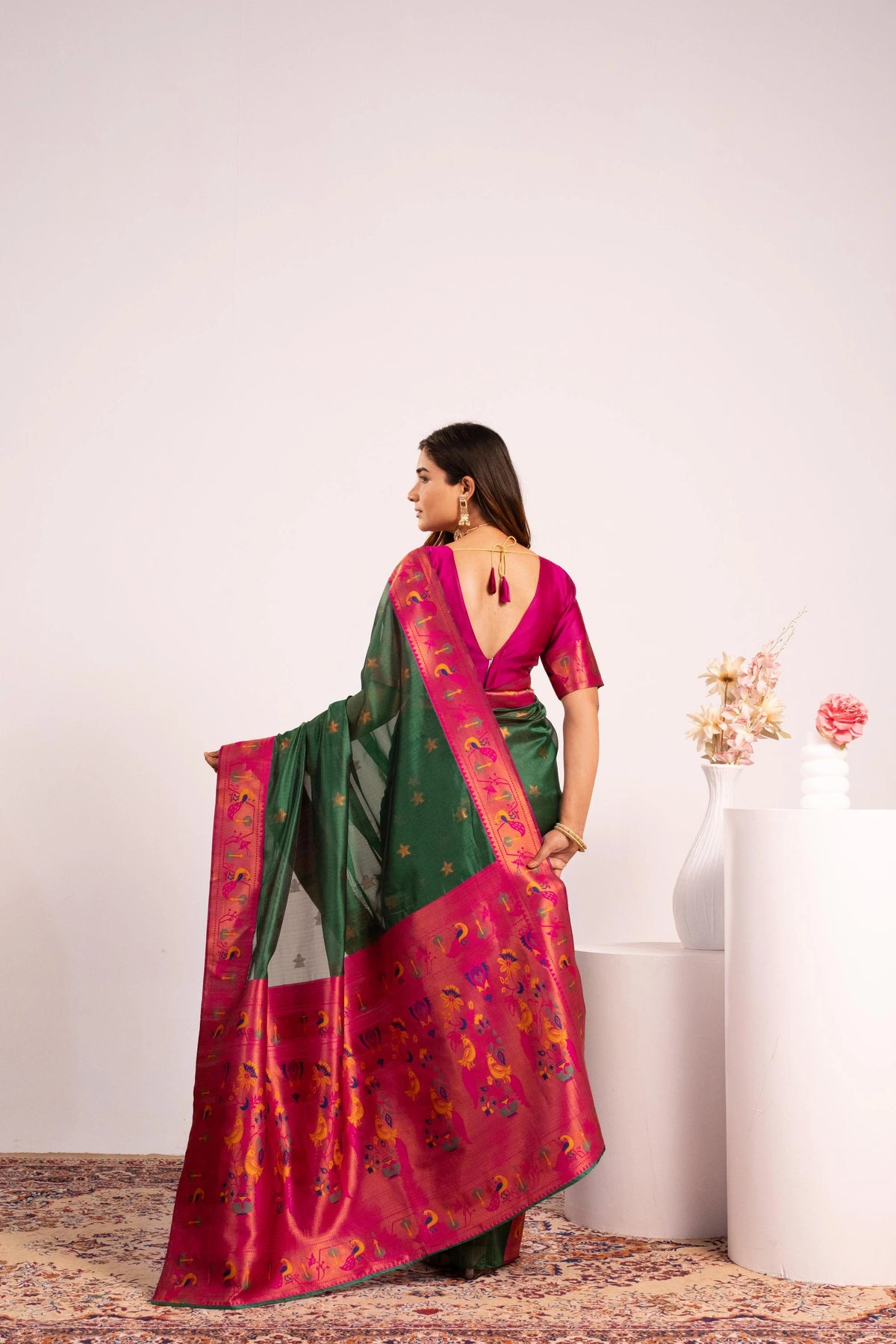 Woman wearing a pink and green saree with a white background