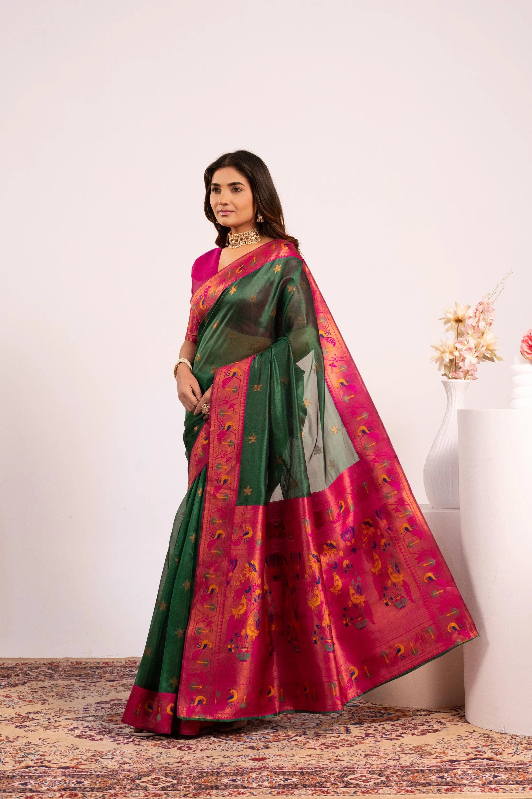 Woman wearing a green and pink saree with a white background
