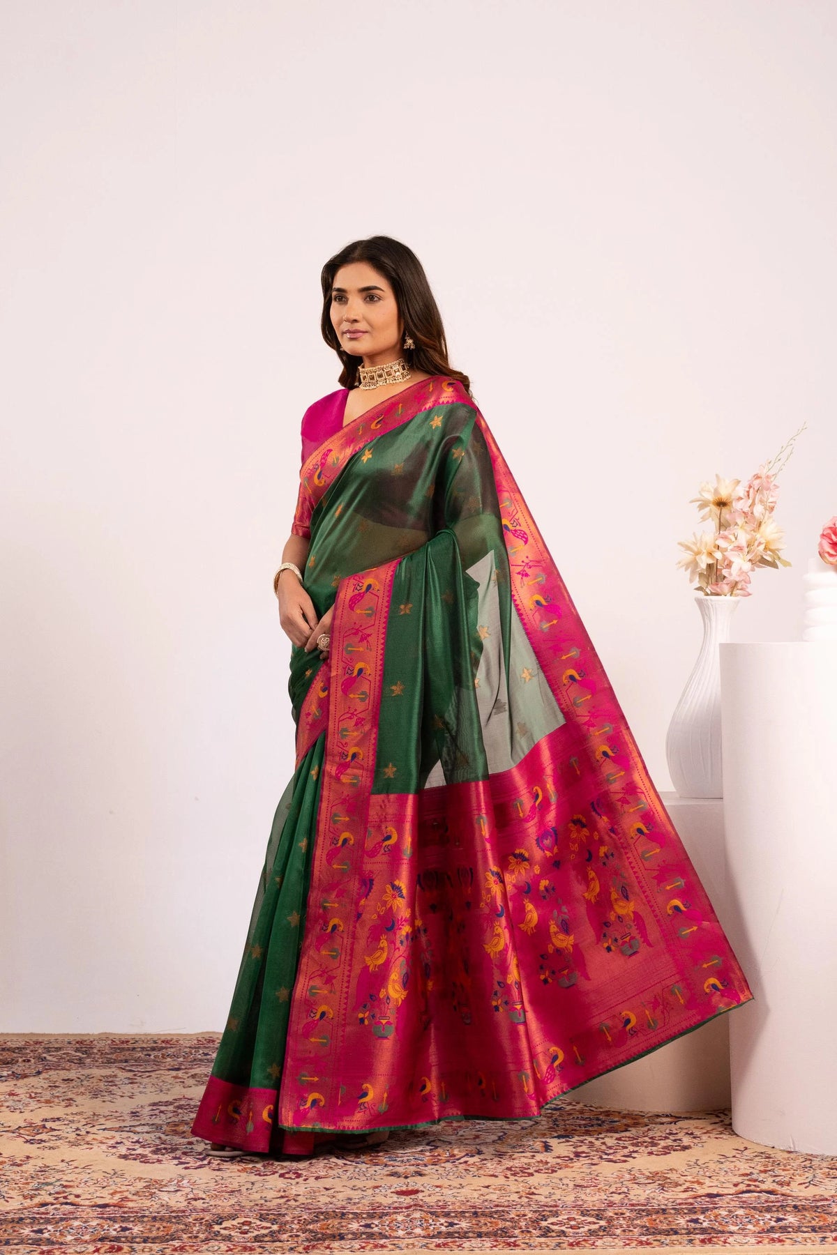 Woman wearing a green and pink saree with a white background