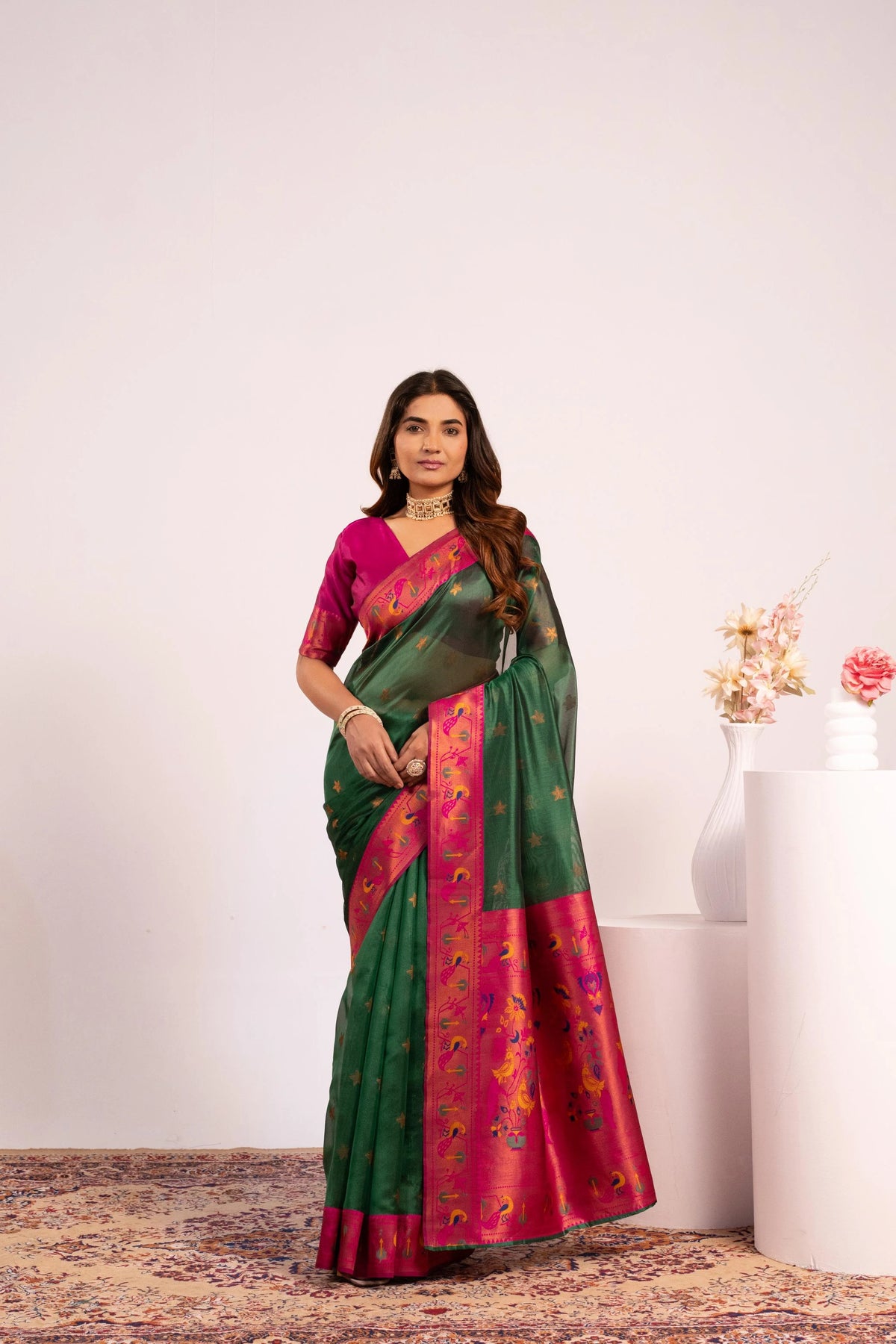 Woman wearing a green and pink saree with a white background