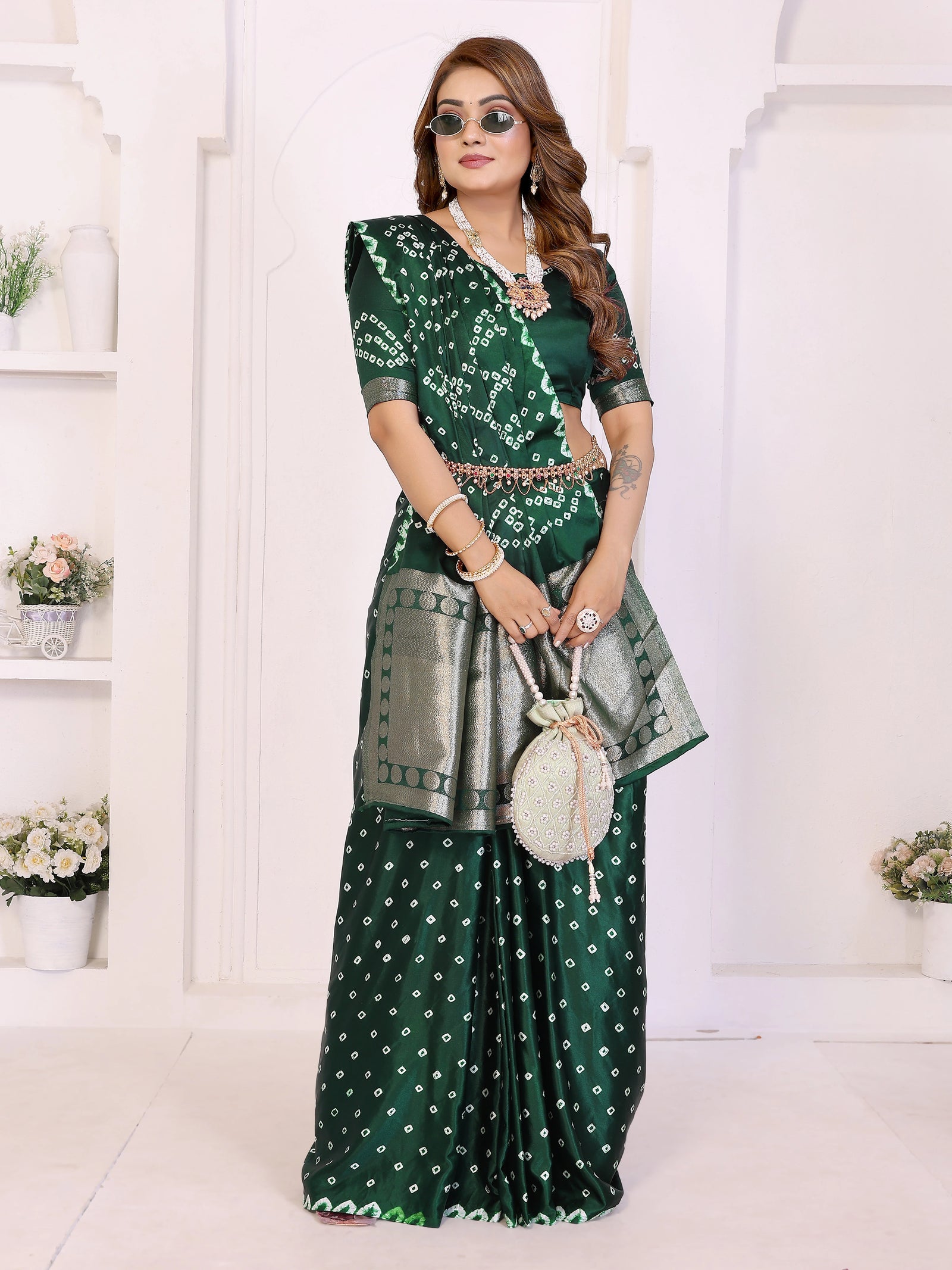 Woman wearing a green saree with silver blouse in a white room.