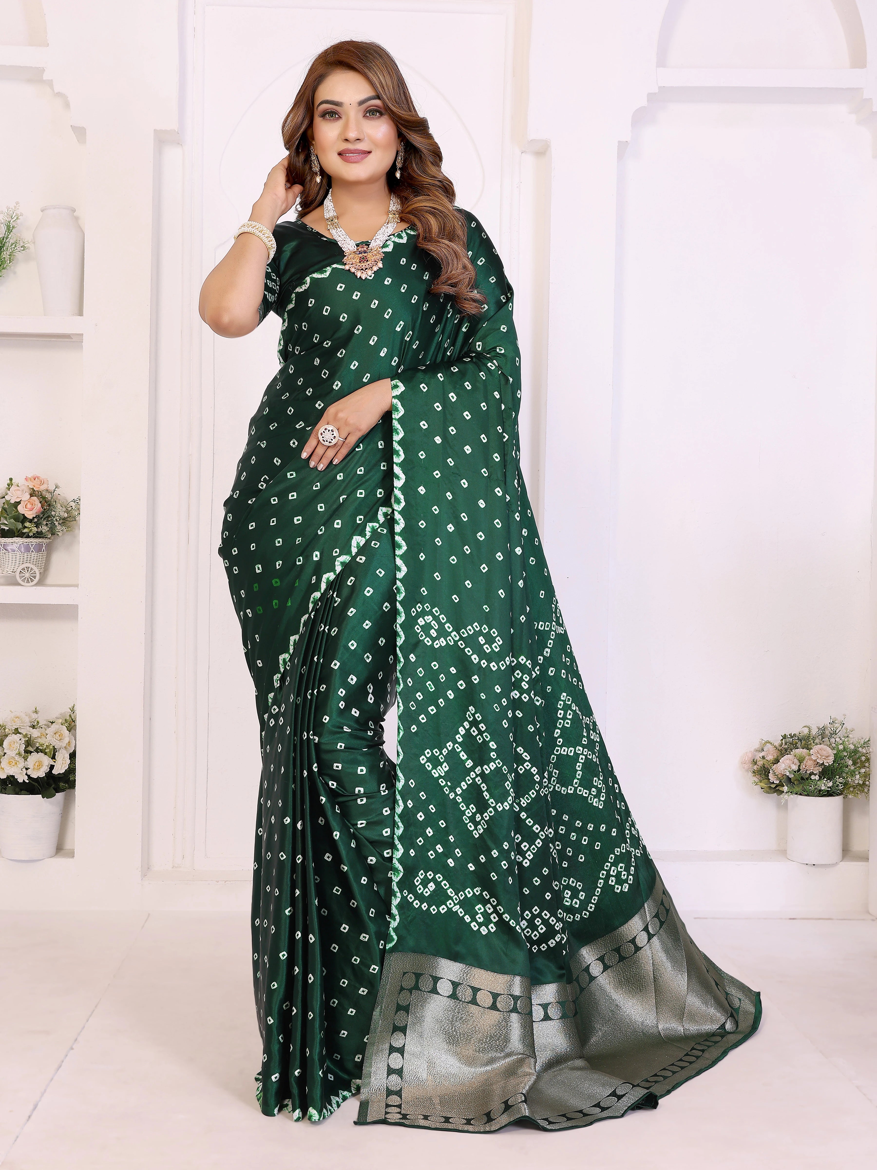 Woman wearing a green saree with white patterns in a white room.