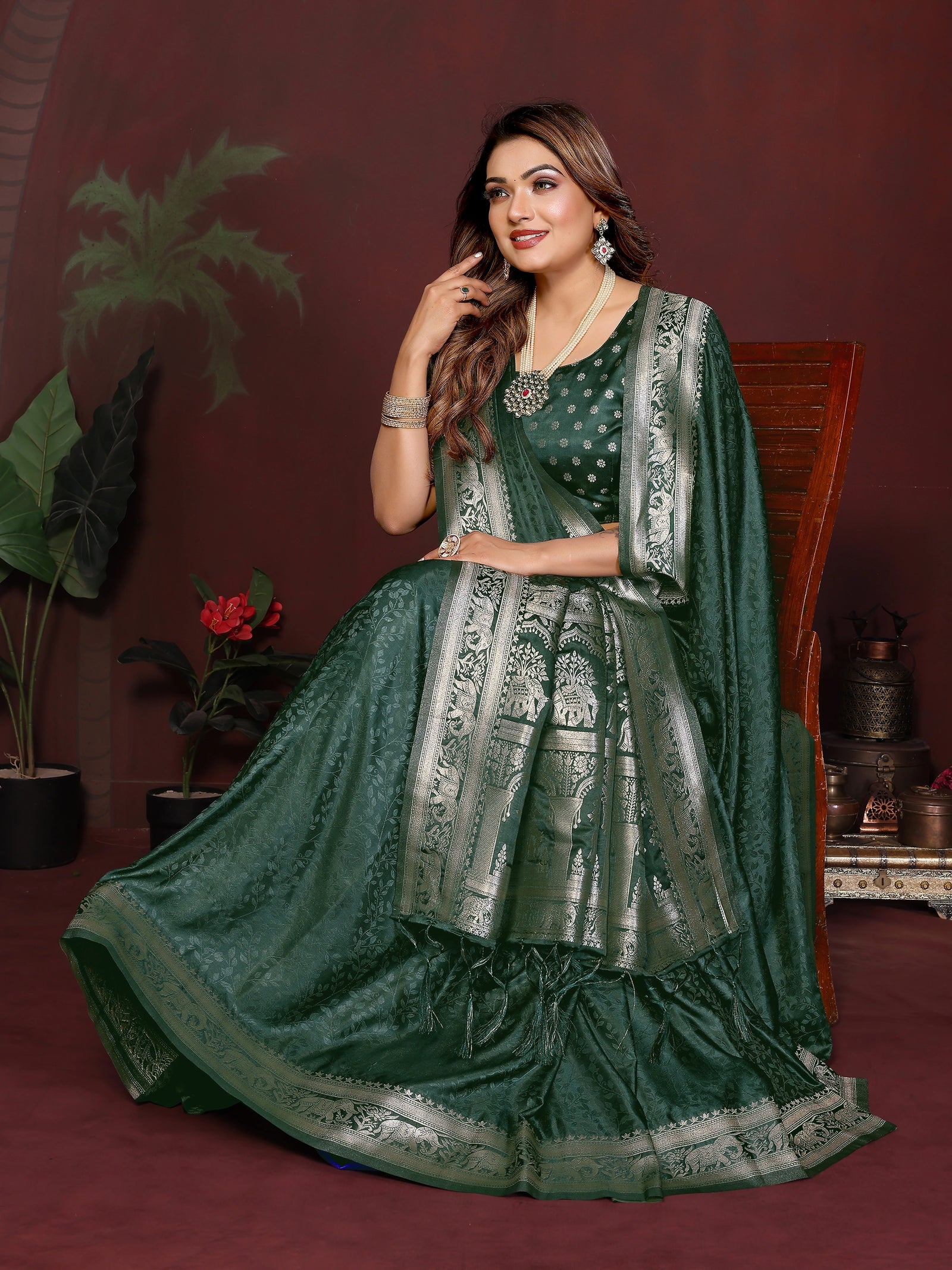Woman in a green traditional outfit with silver details against a maroon background