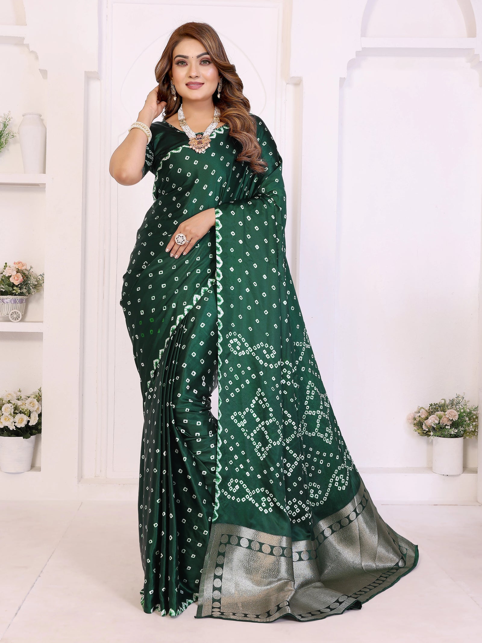 Woman wearing a green saree with white patterns in a white room.