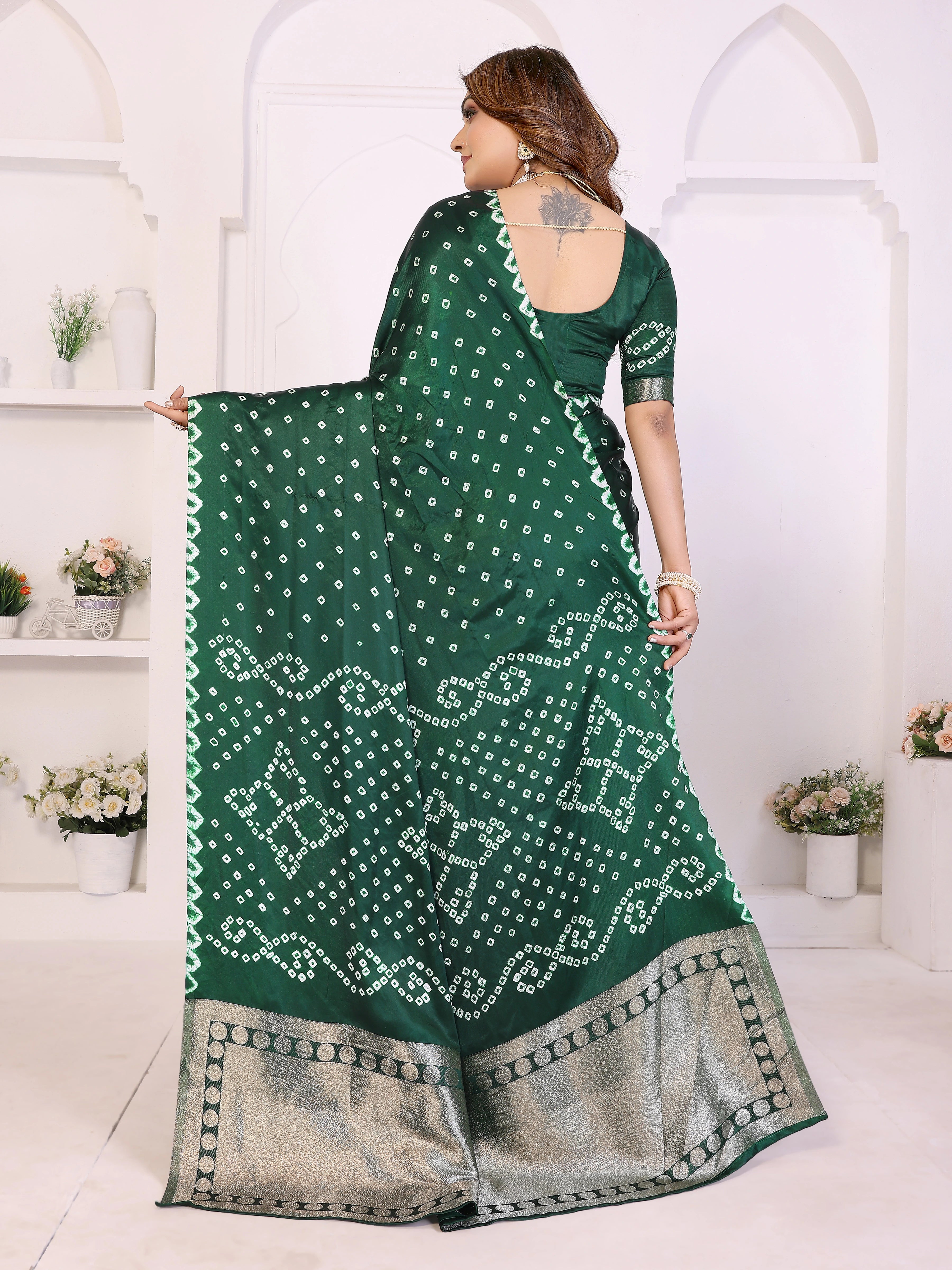 Woman holding a green saree with white patterns in a white room.