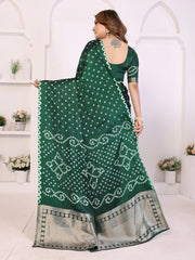 Woman holding a green saree with white patterns in a white room.