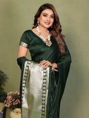 Woman wearing a green saree with a white border against a plain background