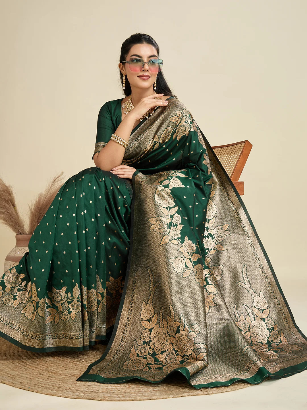 Woman wearing a green and gold saree with floral patterns on a beige background