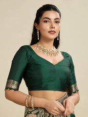 Woman wearing a green saree with gold jewelry on a beige background