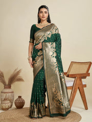 Woman wearing a green and gold saree with a beige background