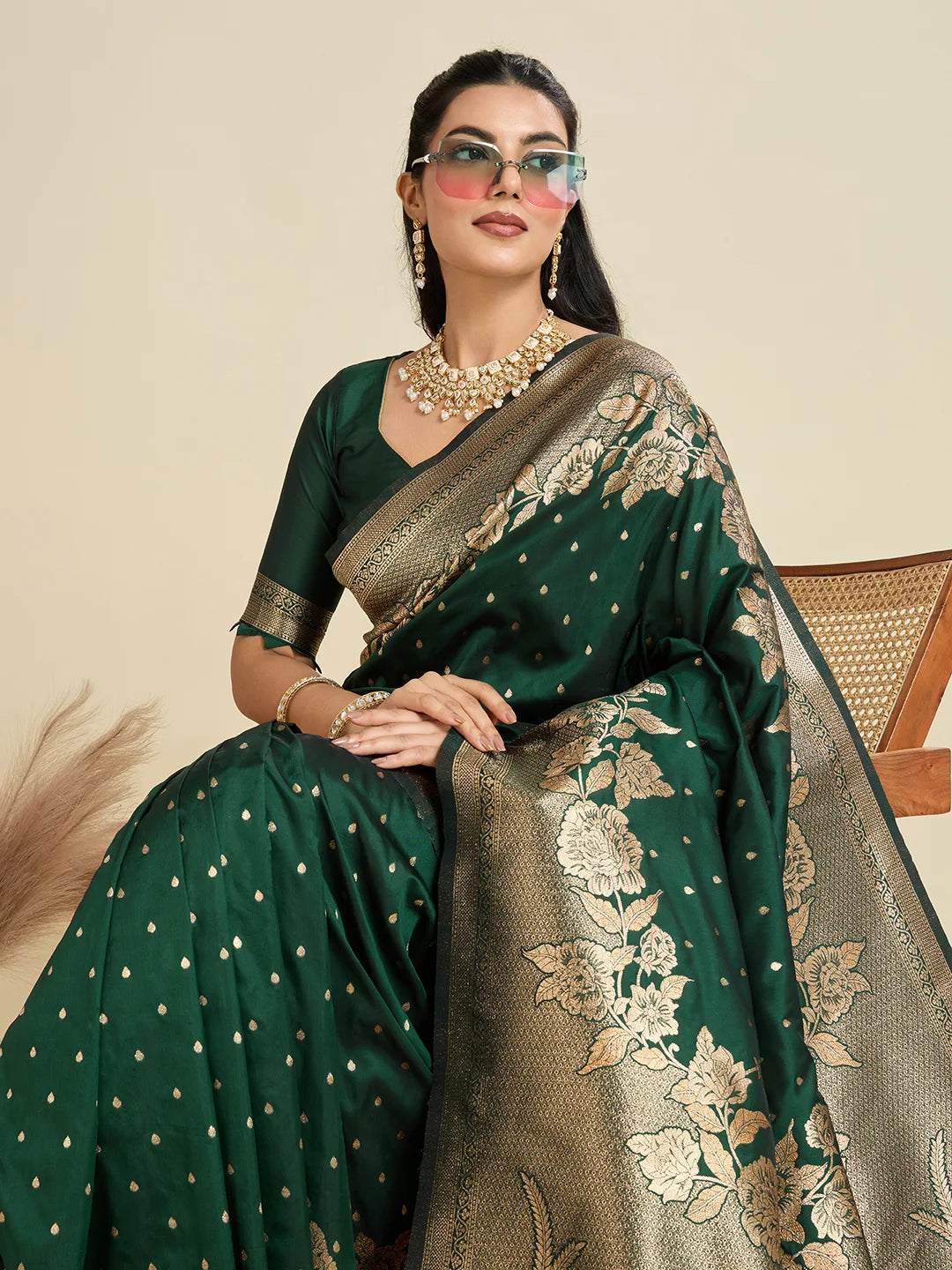 Woman wearing a green saree with gold patterns against a beige background