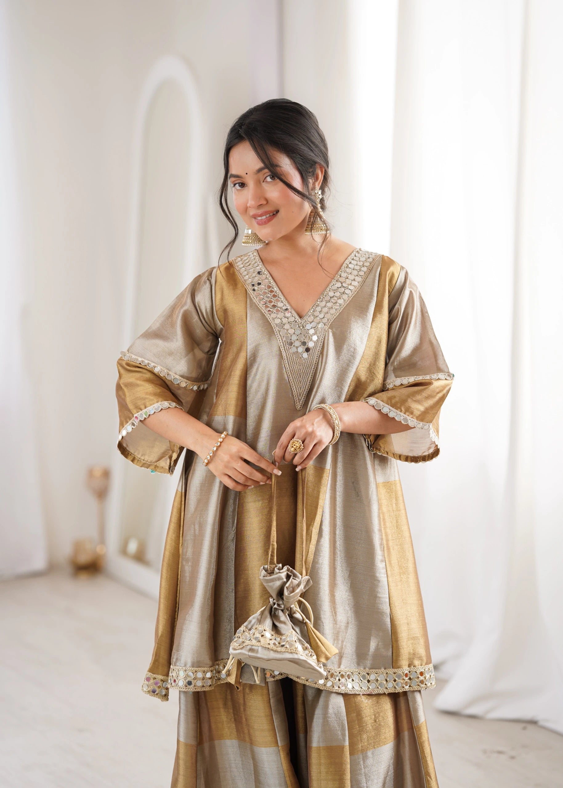 Woman wearing a gold and beige traditional outfit with intricate designs.