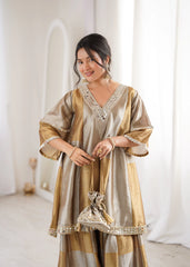 Woman wearing a gold and beige traditional outfit with intricate designs.