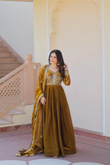 Woman in a gold traditional outfit standing in a room with a staircase.