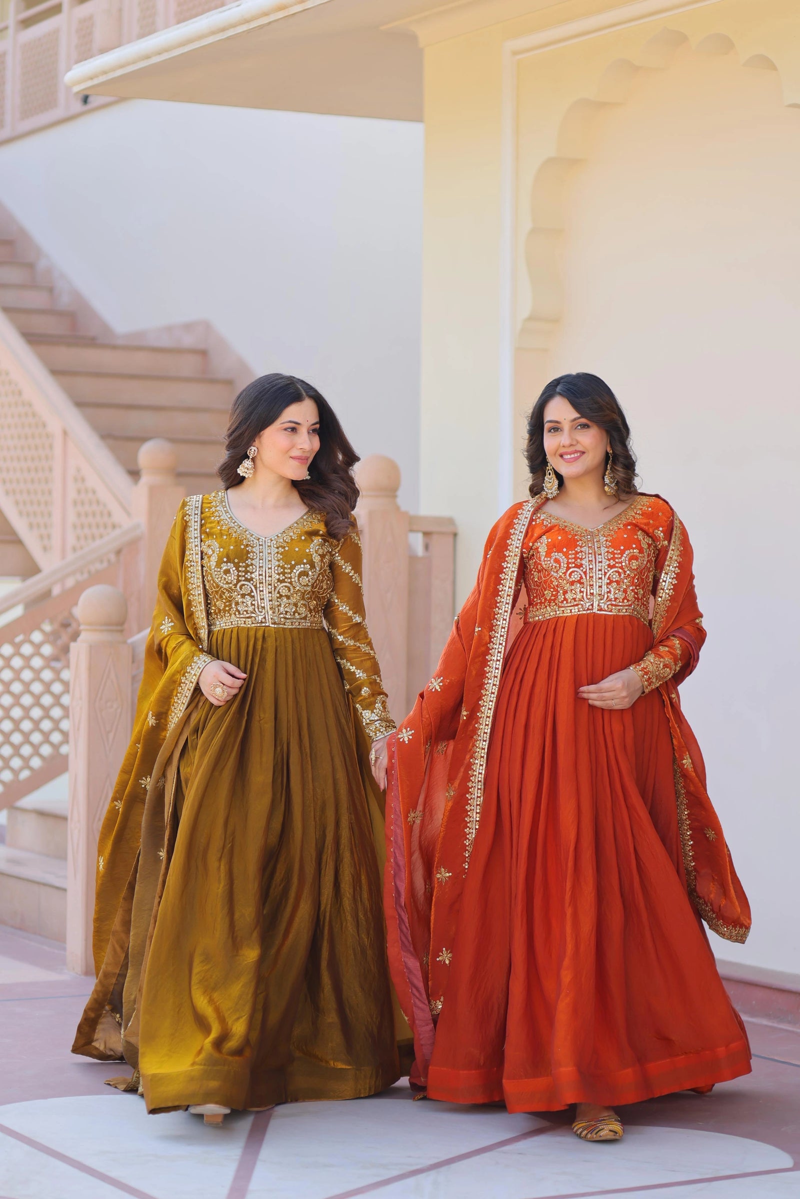 Two women in traditional embroidered dresses standing on a staircase.
