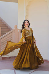 Woman in a mustard yellow traditional outfit standing in a decorative interior setting.