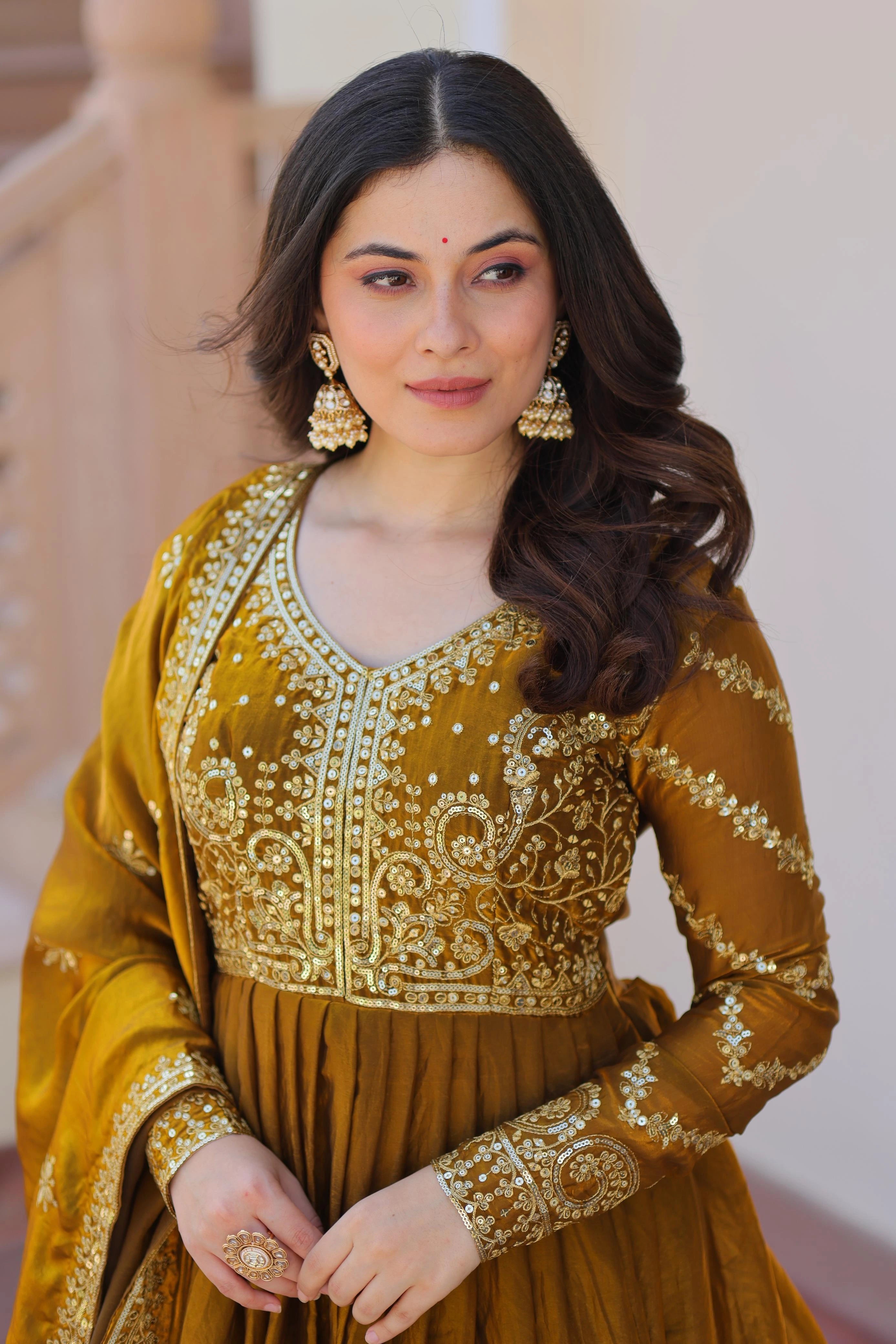 Woman wearing a mustard yellow traditional outfit with intricate designs.