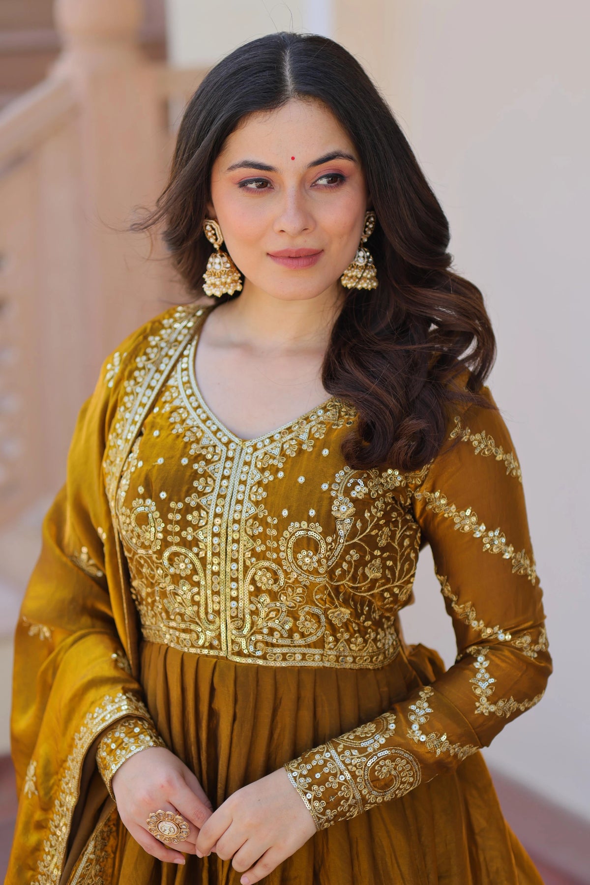 Woman wearing a mustard yellow traditional outfit with intricate designs.