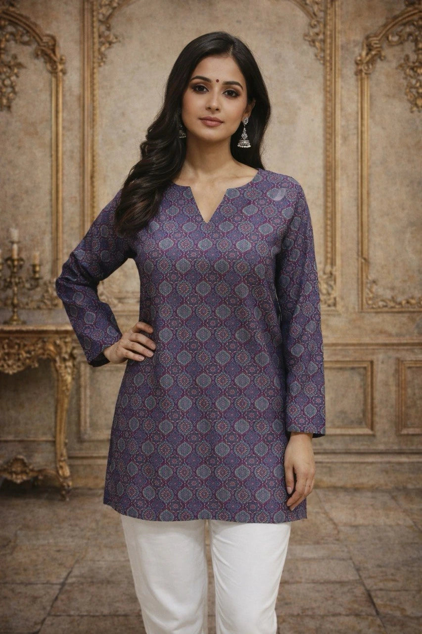 Woman wearing a patterned purple kurta with white pants in an ornate room.