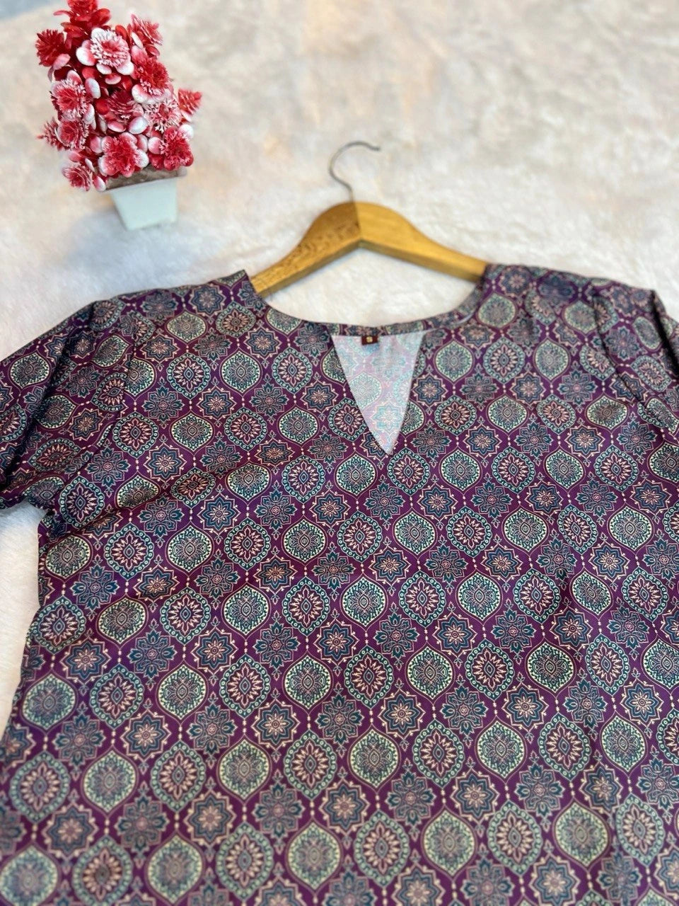 Patterned shirt on a hanger with a decorative vase and flowers in the background