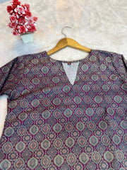 Patterned shirt on a hanger with a decorative vase and flowers in the background