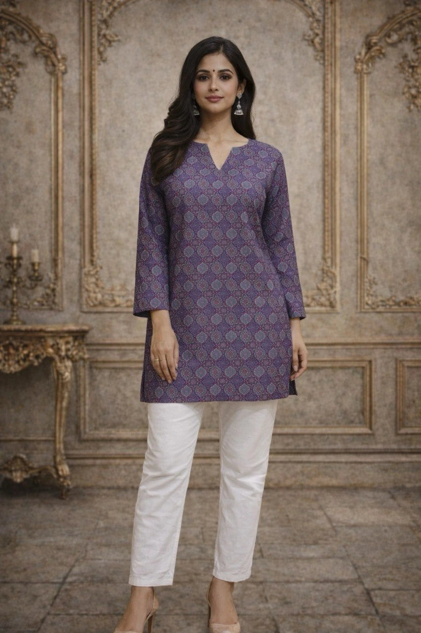 Woman wearing a purple patterned kurta with white pants in an ornate room.